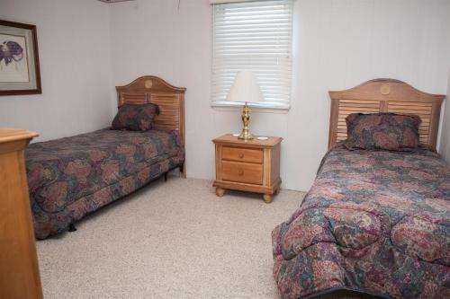 a bedroom with two beds and a table with a lamp at 57218 Island Club Lane Home in Hatteras