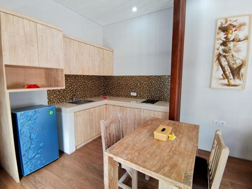 a kitchen with a wooden table and a blue refrigerator at Kuta Puri Bungalows, Villas and Resort in Kuta