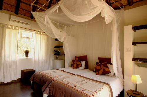 帕拉博魯瓦的住宿－諾曼野生叢林酒店，一间卧室设有天蓬床和窗户。
