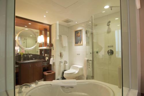 a bathroom with a tub and a toilet and a shower at Plaza Hotel Yuyao in Yuyao