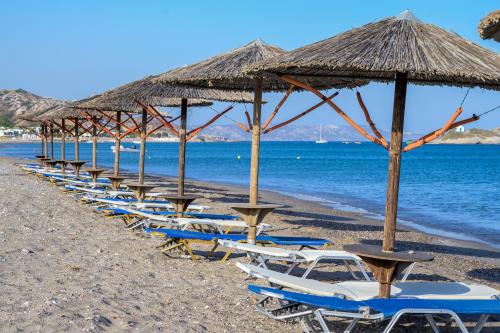a row of chairs and umbrellas on a beach at Royal Bay Suites in Kefalos