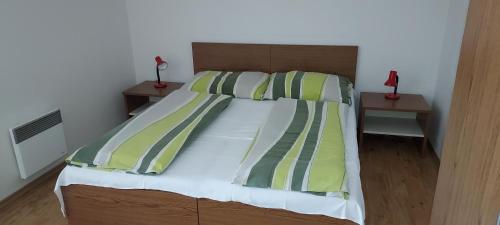 a bed with green and white sheets and pillows at Aparthotel Rezidence Club Canada Lipno in Lipno nad Vltavou