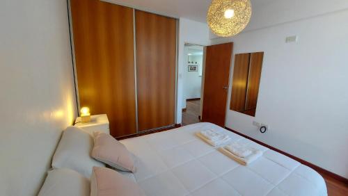 a bedroom with a large white bed and a mirror at Cálido y hermoso Dpto. en excelente zona de Rosario in Rosario