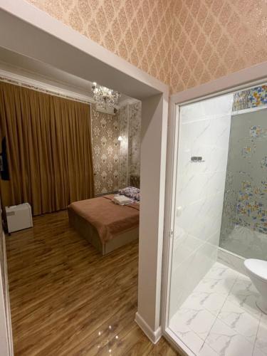 1 dormitorio con 1 cama y baño con ducha. en Гостиница АСКАР, en Shymkent