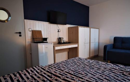 a small room with a bed and a kitchen with a blue wall at Serce Kaszub. Pokoje z niezależnym wejściem. in Swarzewo