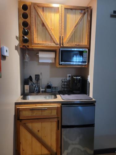 a kitchen with wooden cabinets and a sink and a microwave at The Colburn Schoolhouse - Geography suite in Sandpoint
