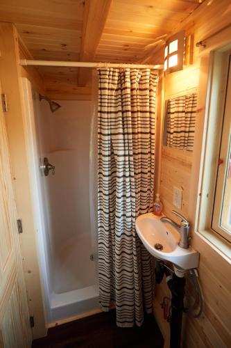 a small bathroom with a sink and a shower at Tuxbury Pond Camping Resort Tiny House Emerson in South Hampton