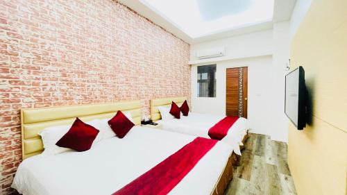 two beds in a room with a brick wall at Jabez B&B in Jiaoxi