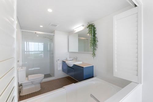 a white bathroom with a toilet and a sink at Azure Sea Whitsunday Resort in Airlie Beach