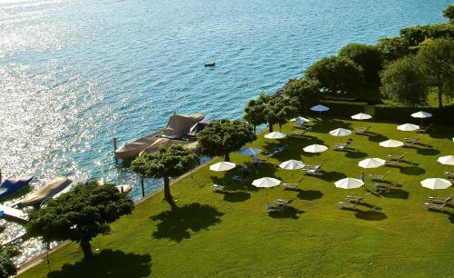 a group of umbrellas and chairs on the grass near the water at HERMITAGE Lake Lucerne - Beach Club & Lifestyle Hotel in Luzern