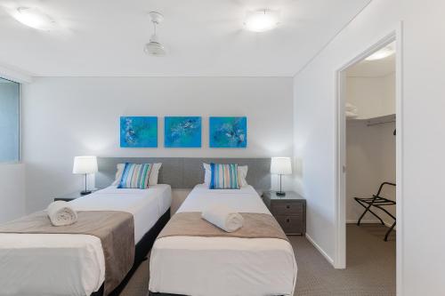 two beds in a room with white walls at Azure Sea Whitsunday Resort in Airlie Beach