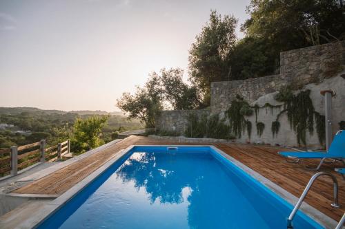 una piscina con terraza de madera y una silla junto a un edificio en Corfu Tramezzo designer's House, en Bastoúnion