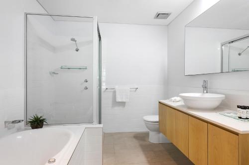 a bathroom with a tub and a toilet and a sink at Azure Sea Whitsunday Resort in Airlie Beach