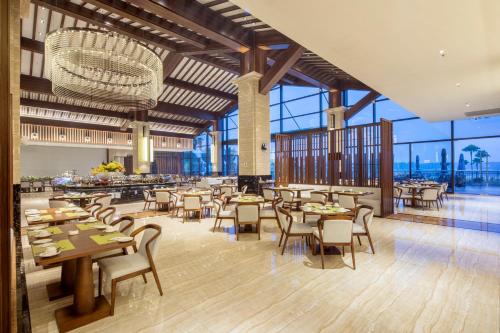 un restaurante con mesas, sillas y ventanas grandes en Forest City Golf Hotel en Nusajaya