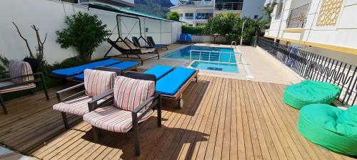 a deck with chairs and a table and a swimming pool at Kara Family Apart in Kemer