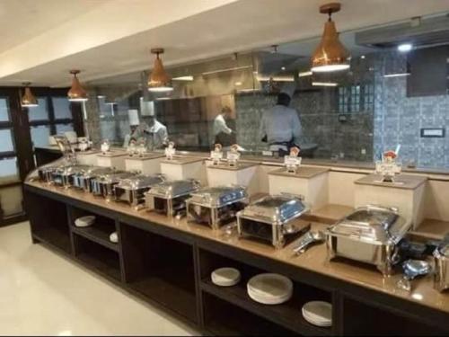 a kitchen with a counter with people preparing food at Hotel Atithi in Guwahati