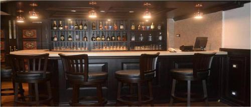 a bar with wooden chairs and bottles of wine at Hotel Atithi in Guwahati