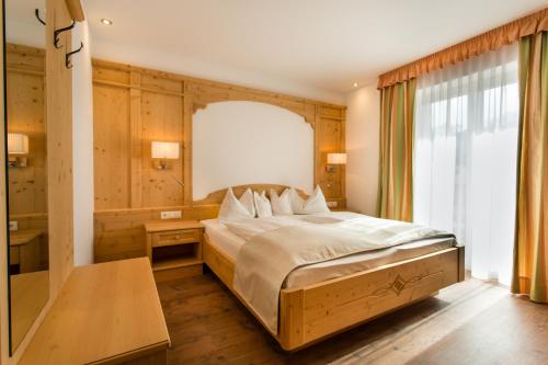 a bedroom with a large bed and a window at Hotel Rosskopf in Vipiteno