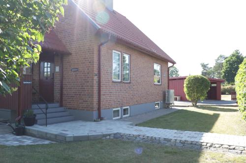 a red brick house with a grass yard at Kärraton Stugor Centrala Åhus in Åhus