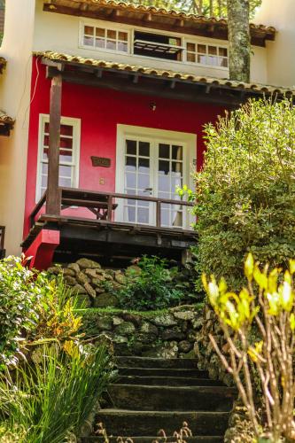 a red house with a porch and stairs in front at Pousada dos Ingleses in Bombinhas