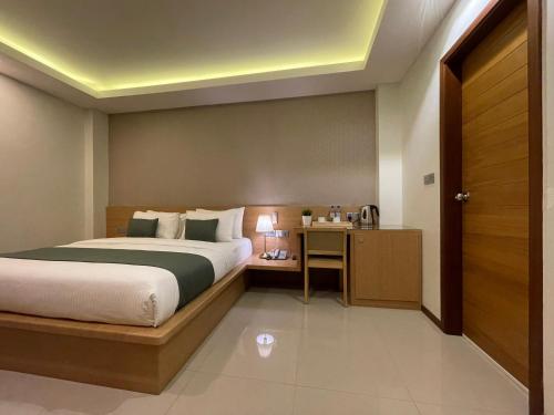 a hotel room with a bed and a desk and a door at Huvan Beach Hotel at Hulhumale in Hulhumale
