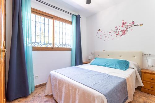 Schlafzimmer mit einem Bett mit blauen Vorhängen und einem Fenster in der Unterkunft Apartamento con piscina privada in Nerja