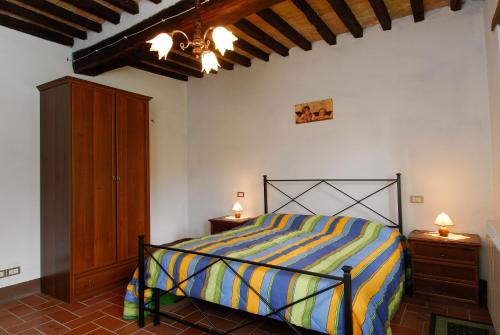 ein Schlafzimmer mit einem Bett mit einer gelben und blauen gestreiften Decke in der Unterkunft A stay surrounded by greenery - Agriturismo La Piaggia -app 3 guests in Vivo dʼOrcia