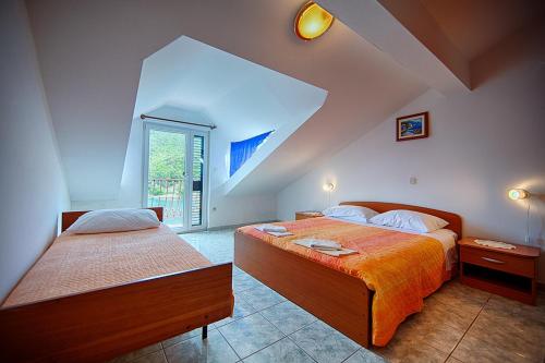 a attic bedroom with two beds and a window at Apartments Malo Lago in Lastovo