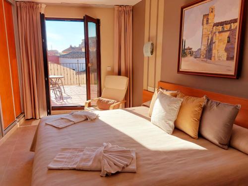um quarto de hotel com uma cama grande e uma varanda em HOTEL RURAL San Pedro em Frómista