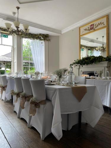 a dining room with white tables and chairs and a mirror at The Silk House in Leek