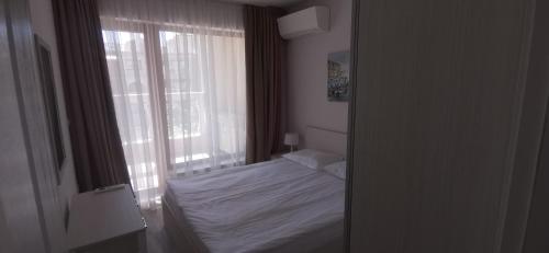 a bedroom with a white bed and a window at La Mer Apartcomplex and Spa in Golden Sands