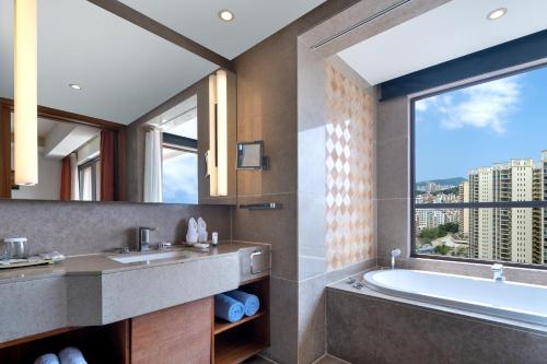 een badkamer met een bad, een wastafel en een raam bij Mangrove Tree Resort World Sanya Bay-Kapok in Sanya