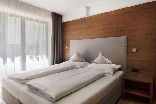 a bedroom with a large white bed and a window at Apartments Montblanc Sella in Ortisei