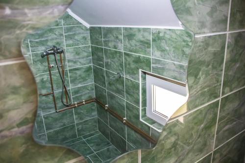 a bathroom with green tiled walls and a window at Sóhegy Panzió in Praid