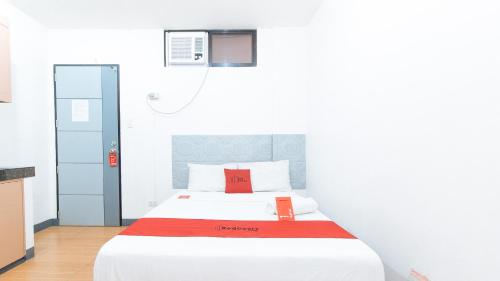 - une chambre avec un lit blanc et une couverture rouge dans l'établissement RedDoorz CAA Road Las Pinas, à Manille