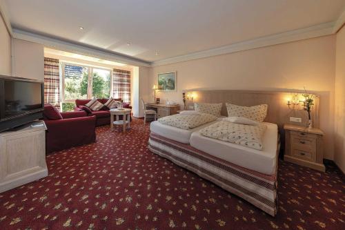 a bedroom with a large bed and a living room at Hotel Historischer Krug in Oeversee