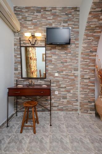 a vanity with a mirror and a tv on a brick wall at Orama Apartments in Agia Anna Naxos