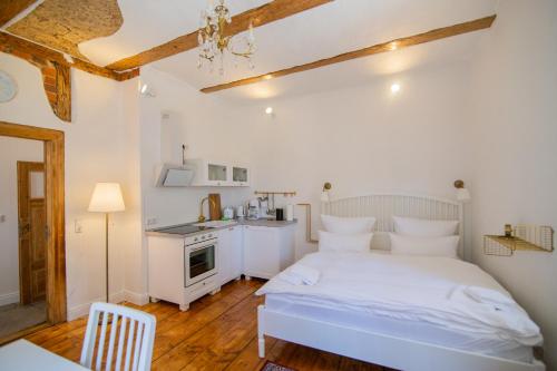 a bedroom with a white bed and a kitchen at ApartOne Palais-Apartments in Bautzen