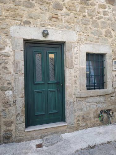 una puerta verde en el lateral de un edificio de piedra en Spitaki traditional house, en Vóroi