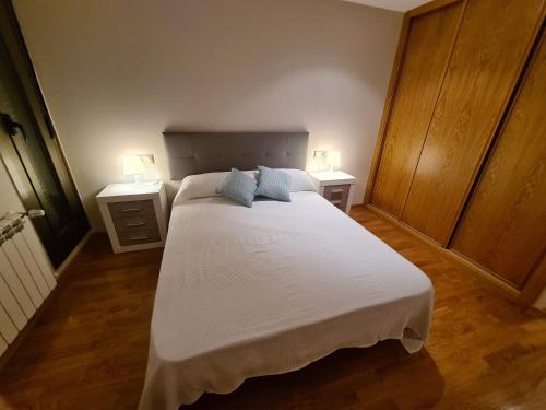 1 dormitorio con 1 cama blanca grande y 2 mesitas de noche en APARTAMENTOS VIVE en Viveiro