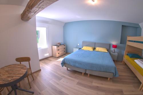 a bedroom with a blue bed and a wooden floor at Au pré des acajous in Pertheville-Ners