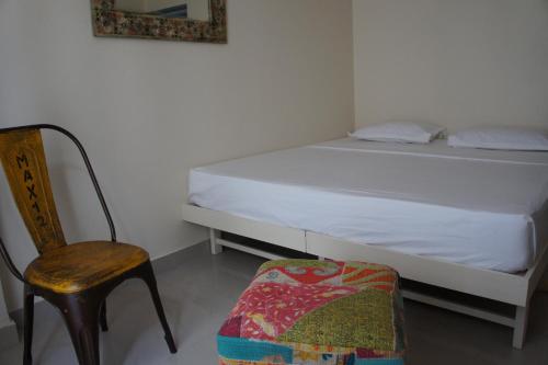 a small bedroom with a bed and a chair at Bed & Chai Guesthouse in New Delhi