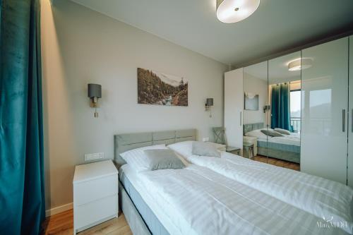 a bedroom with a large white bed and a mirror at Apartament Silence Karpatia Resort Zelda in Karpacz