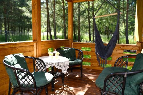 a porch with a table and chairs and trees at Domek pod Sosnami z posesją na wyłączność Mazury Prażmowo in Prażmowo