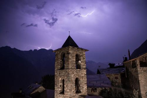 a lightning storm over a building with a tower at Casa Rural Borda Marianet in Cerler