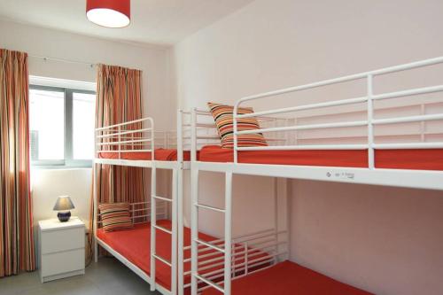 1 Schlafzimmer mit 2 Etagenbetten mit roter Bettwäsche in der Unterkunft Mellieha_1, Waterfront - Sea Sun & History in Mellieħa