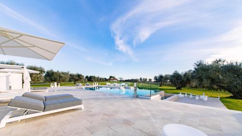 a patio with a pool and chairs and an umbrella at La Perla tra gli Ulivi 12, Emma Villas in San Vincenzo