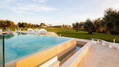 a large swimming pool with chairs and a lawn at La Perla tra gli Ulivi 12, Emma Villas in San Vincenzo