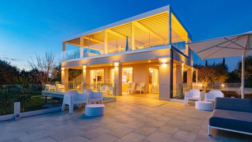 a house with a patio with white chairs and tables at La Perla tra gli Ulivi 12, Emma Villas in San Vincenzo