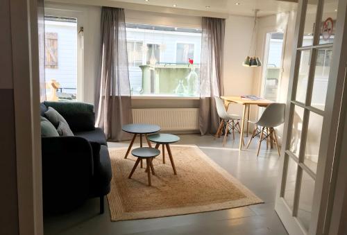 uma sala de estar com um sofá e duas mesas em Houseboat apartment with water terrace, free parking, free bikes & fast wifi em Amsterdã